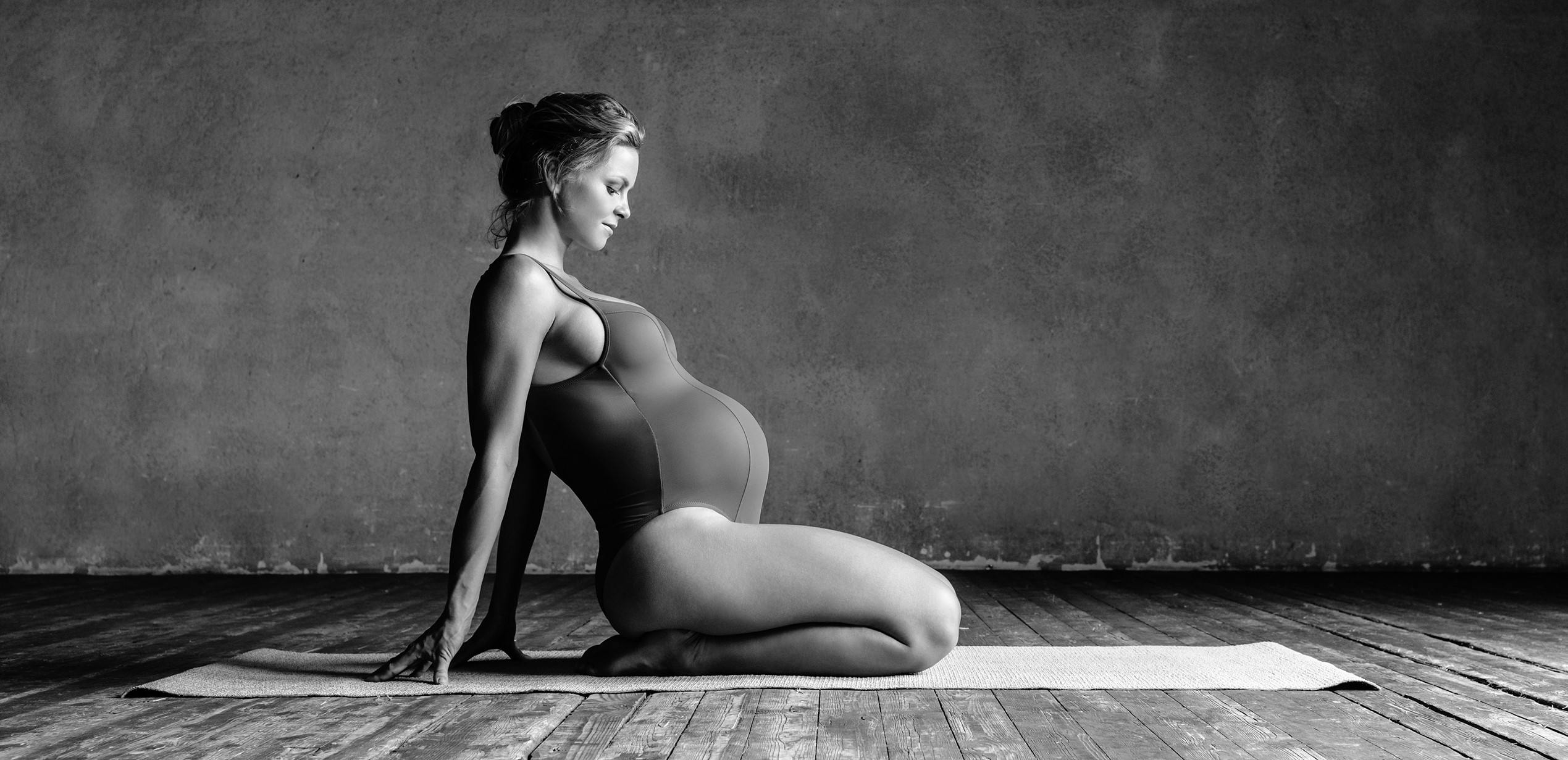 Young beautiful prentant woman is posing in studio
